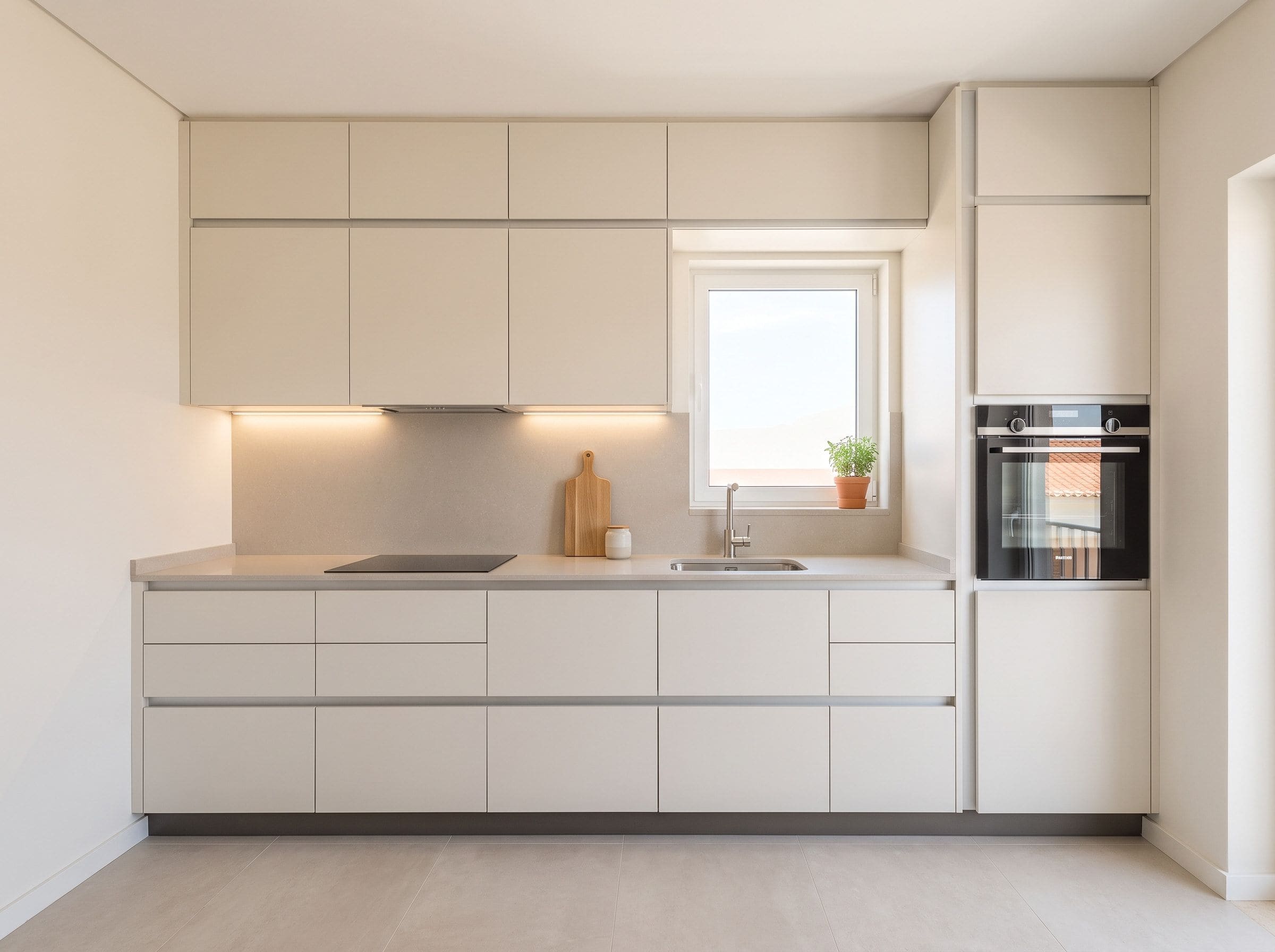 Cozinha compacta de apartamento com armários até ao teto e bancada de trabalho desimpedida